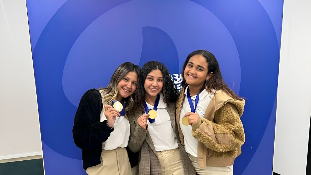 Three girls smiling wearing gold medals