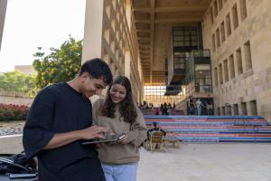 Girl and a boy looking at an ipad on campus outdoors