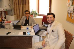 Two men sitting in an office on their laptops smiling