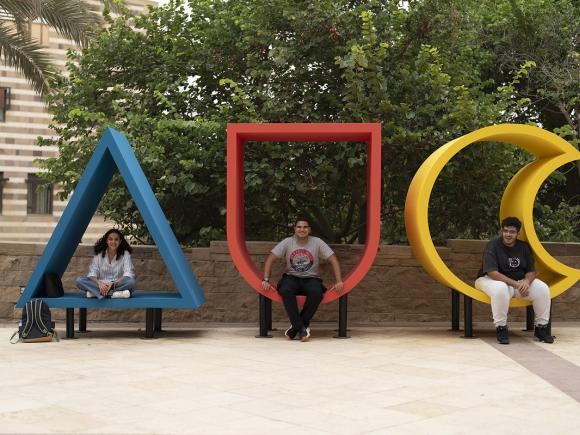 three students sitting in three letters